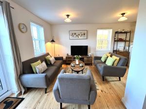 ein Wohnzimmer mit zwei Sofas und einem Fernseher in der Unterkunft Cosy Cotswold Home - Jacobs Cottage in Cirencester