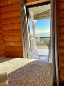 a bedroom with a bed and a large window at Private Mountain Log Cabin with amazing panoramic sunset views at small scale nature resort in Cabeceiras de Basto
