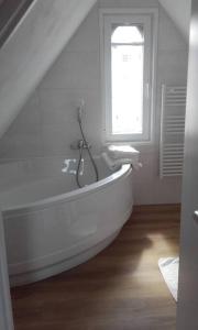 een witte badkamer met een bad en een raam bij Maison rénovée atypique, jardin, terrasse, Odet in Quimper