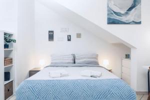 a white bedroom with a bed with a blue comforter at Loft - Comfort Studio - [10m Piazza Maggiore] in Bologna
