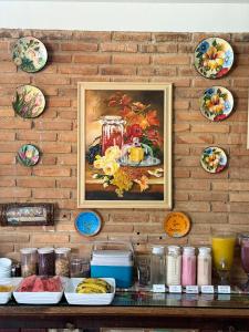 a painting hanging on a brick wall with plates at Pousada Ecos do Mar in Praia do Frances