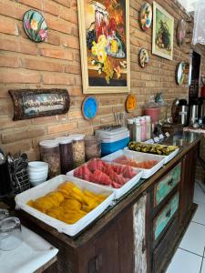 a counter with several trays of different types of food at Pousada Ecos do Mar in Praia do Frances