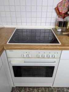 La cocina está equipada con fogones blancos. en Praktisches Gästezimmer für eine Person, en Bergisch Gladbach