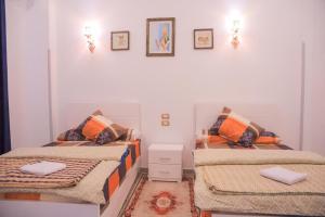 two beds in a small room with pictures on the wall at Villa Desert Rose in Luxor