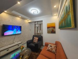 uma sala de estar com um sofá e uma televisão na parede em Khomes cosy studio em Nairobi