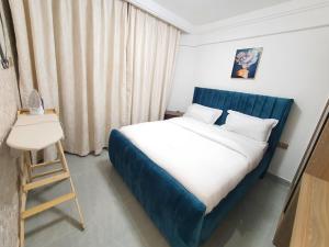Schlafzimmer mit einem Bett mit blauem Kopfteil und einem Stuhl in der Unterkunft Khomes cosy studio in Nairobi