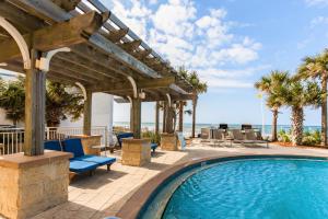 a swimming pool with a pergola and chairs and the ocean at Aqua 801 in Panama City Beach