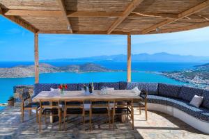 a table and chairs on a patio with a view of the ocean at Luxury Villa Orea, Elounda (owner's listing) in Epáno Eloúnda