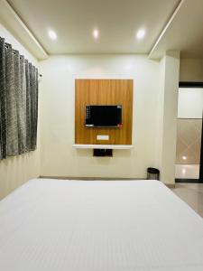 a bedroom with a bed and a tv on the wall at HOTEL EKANT FAMILY RESTAURANT AND LODGING in Daulatābād
