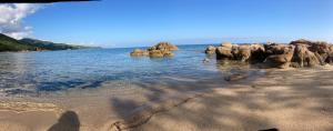 a beach with some rocks in the water at Villa l'Alpana en bois vue mer a 180 degres in Sari Solenzara