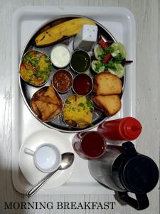 taca z talerzem jedzenia na stole w obiekcie HOTEL REST INN w mieście Surat