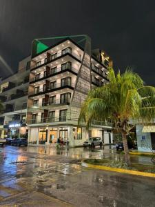 un edificio con una palma di fronte di Alizee Tower a Playa del Carmen