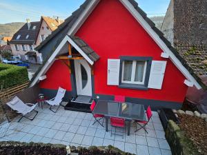 een rood huis met stoelen en een patio bij Gîte Vallée de Munster chez Flavie & Ludo in Muhlbach-sur-Munster