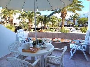 a white table and chairs on a patio with palm trees at Happy Heart Los Molinos in Costa Teguise