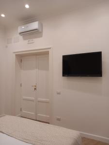 Habitación con TV de pantalla plana en la pared en Porto 55 en Nápoles