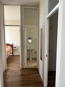 a hallway with a bathroom with a sink and a bed at Confortable Departamento Nuevo in Tarapoto