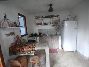 a kitchen with a refrigerator and a table and a sink at Chalé Mar Aberto in Porto Seguro