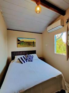 um quarto com uma cama branca e uma janela em Casa Beco do Céu em Fernando de Noronha