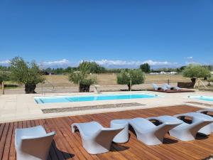 a pool with white chairs on a wooden deck at Entrevides, Tupungato, Valle de uco in Tupungato