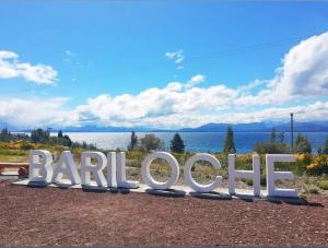 um grande sinal que lê bariloto em frente à água em Las Victorias Suites Bariloche em San Carlos de Bariloche