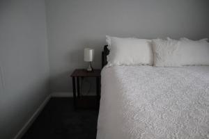 バーネットにあるCharming 3Bed Home in High Barnetのベッド(白い枕付)、テーブル(ランプ付)