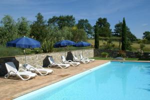 een rij stoelen en parasols naast een zwembad bij Agriturismo Mulinaccino in Fabro