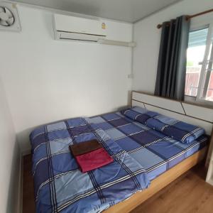 um quarto com uma cama com lençóis azuis e uma janela em PA House Apartment em Banguecoque