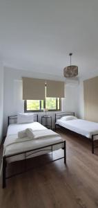 two beds in a large room with wooden floors at Cozy & Minimal Apartment Near Airport Peania in Paianía