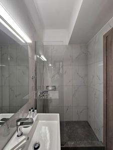 La salle de bains blanche est pourvue d'un lavabo et d'une douche. dans l'établissement Cozy & Minimal Apartment Near Airport Peania, à Paianía