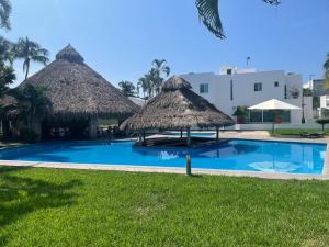 ein Pool mit zwei Strohschirmen und ein Resort in der Unterkunft Casa Sirena 18 in Manzanillo