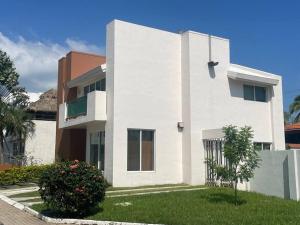 een wit huis met een boom ervoor bij Casa Sirena 18 in Manzanillo