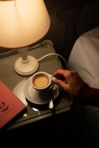 uma pessoa segurando uma xícara de café em uma mesa em BDB Rooms Navona em Roma