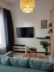 ein Wohnzimmer mit einem Sofa und einem Flachbild-TV in der Unterkunft Le Studio de la Seine in Elbeuf