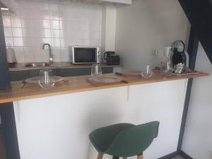eine Küche mit einer Theke und einem grünen Stuhl in der Unterkunft Le Studio de la Seine in Elbeuf