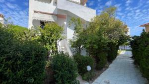 a white building with trees and a walkway at Sofia's house in Possidi