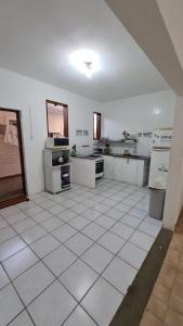 a large kitchen with white tiled floors and appliances at Hostel Praia 102 in Ubatuba +23 photos