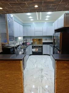 una grande cucina con armadi bianchi e pavimento in marmo di شقة ألترا لوكس بالمهندسين a Il Cairo
