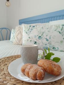 two donuts on a plate on a table with a cup at Zabbàra B&B in Terrasini