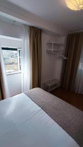 a bedroom with a white bed and a window at The River House in Peso da Régua