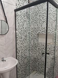 a bathroom with a glass shower and a sink at Pousada Luz Beira mar in Tramandaí