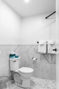 a white bathroom with a toilet and towels at The Phenix Historic DTWN Hotel, King Bed Room #300 in Bangor