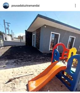 a playground with a slide in front of a house at Pousada Luz Beira mar in Tramandaí