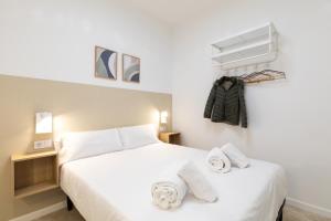 a bedroom with a white bed with towels on it at Pensión Alicante by Moontels in Valencia