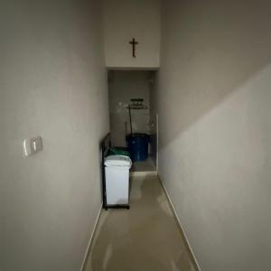 a hallway with a white trash can and a cross on the wall at Hostal la guadalupana in Necoclí