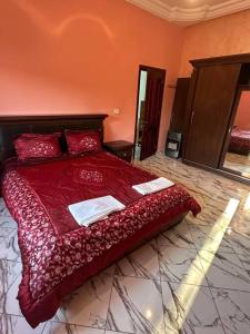 a bedroom with a red bed with two towels on it at Villa spacieuse 200 m à la plage in Zarzis