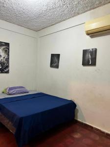a bedroom with a blue bed and pictures on the wall at hostal y Restaurante Entre Olas in La Libertad