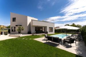 uma casa com piscina, cadeiras e guarda-sol em Villa Costa em Funtana