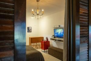um quarto com uma cama, uma televisão e um lustre em Apartamento Le Quatre Centro Monte Verde em Monte Verde