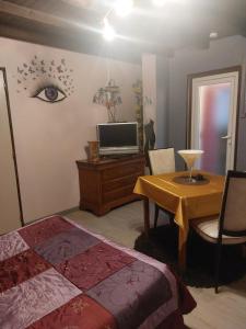 Un dormitorio con una cama y una mesa con televisión. en Sci la MIJOTIERE, en Fourques-sur-Garonne