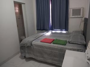 um quarto com uma cama com duas almofadas vermelhas e verdes em 2 quadras do mar em Vila Velha